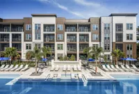 Contemporary apartment complex with poolside luxury featuring sleek architecture, lush palm trees, and sunny lounge area perfect for relaxation.