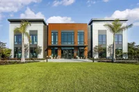 Modern apartment building with a sleek design, large windows, and lush green lawn accented by palm trees, promising luxury and style.