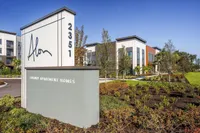 Modern luxury apartment complex featuring sleek architecture and beautifully landscaped gardens, highlighted by a prominent entrance sign with the address 2351.