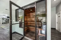 Modern gym facility featuring a luxurious wooden sauna with glass doors, offering a perfect retreat for relaxation and wellness.
