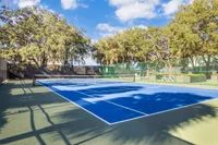 Inviting outdoor tennis court surrounded by lush greenery, perfect for a sunny day match.