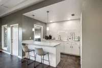 Modern kitchen with sleek white cabinetry, elegant pendant lighting, and a spacious breakfast bar with stylish seating, perfect for entertaining.