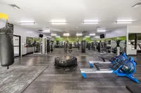 Spacious and modern apartment gym featuring state-of-the-art exercise equipment, sleek flooring, and bright green accents for an invigorating workout experience.