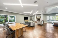 Spacious living area with modern seating, elegant wooden dining tables, and vibrant natural light from large windows, perfect for entertaining and relaxation.