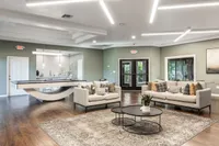 Chic communal living area with elegant sofas, a stylish pool table, and modern open kitchen, offering comfort and sophistication.