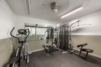Modern apartment gym featuring high-quality fitness equipment, including an elliptical and weight machine in a well-lit space with mirrors.