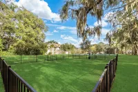Charming outdoor space with lush green lawns, mature trees, and a cozy residential building in the background, ideal for relaxation and leisure.