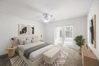 Elegantly furnished bedroom with a cozy bed, stylish decor, and natural light streaming through large glass doors.