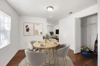 Inviting dining area with a modern round table and elegant chairs, complemented by abstract wall art and warm wooden floors, leading to a stylish living room.
