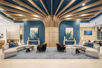 Chic and modern living room with sleek architectural design, featuring elegant curved seating, stylish decor, and eye-catching geometric ceiling accents.