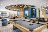 Elegant apartment lounge with stylish billiards table, modern seating, and artistic decor under a striking ceiling design.