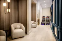 Luxurious lounge space with modern chairs, ambient lighting, and entertaining skee-ball games, highlighted by elegant wooden flooring and stylish decor.