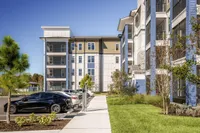 Modern apartment complex exterior with sleek architecture, vibrant landscaping, and electric vehicle charging stations.