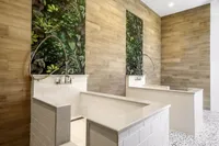 Contemporary pet washing station with sleek white tiling, elegant wood panel accents, and lush greenery, creating a stylish and functional space.