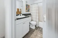 Chic bathroom with elegant white cabinetry, sleek black countertop, modern fixtures, and stylish wall art.