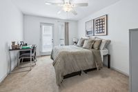 Bright and airy bedroom with a modern design, featuring a plush bed, elegant artwork, and a cozy workspace by a glass door leading to a balcony.