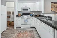 Charming kitchen with modern appliances, granite countertops, and ample pantry storage, accented by elegant white cabinetry and a vintage-style rug.