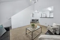 Inviting apartment interior featuring a stylish open-plan living area with a cozy seating space, chic glass coffee table, and modern dining setup, perfect for entertaining.
