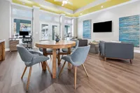Sophisticated living area with sleek wooden flooring, stylish furniture, and a vibrant yellow ceiling, offering modern comfort and elegance.