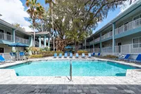 Inviting apartment complex with a sparkling pool surrounded by cozy blue lounge chairs, palm trees, and spacious two-story balconies.