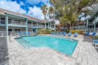 Inviting apartment complex with a pristine pool surrounded by vibrant blue lounge chairs and lush greenery, perfect for relaxation and leisure.