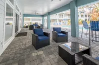 Inviting outdoor lounge area with cozy wicker furniture and poolside views, ideal for relaxation and entertainment.