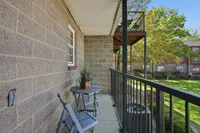Charming balcony view with a cozy seating area, surrounded by lush greenery, perfect for relaxing outdoors.