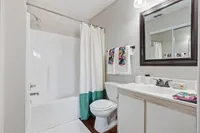 Modern bathroom with elegant fixtures, featuring a spacious shower-tub combination, stylish vanity, and vibrant decorative towels for a touch of color.
