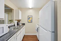 Modern and inviting kitchen with sleek appliances, double sink, and stylish countertop, highlighted by warm wood flooring and cheerful wall art.
