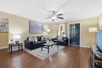 Inviting living room with elegant decor, featuring plush black sofas, tasteful artwork, and a warm ambiance.