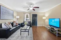 Inviting living room with sleek hardwood floors, black leather sofas, and stylish decor, ideal for relaxation and entertainment.