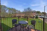 Charming balcony view with stylish seating, overlooking lush green lawns and inviting neighborhood vibes.