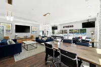Luxurious community room with elegant seating, modern decor, and large windows overlooking a vibrant outdoor pool.