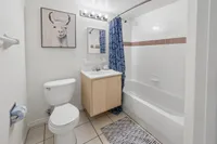 Bright and modern bathroom featuring a stylish llama artwork, elegant vanity, and cozy bathtub with a patterned shower curtain.