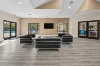 Inviting community room with modern black seating, large windows, and a view of the swimming pool outside.