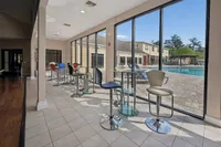 Modern community space with stylish bar seating and floor-to-ceiling windows offering a scenic pool view.