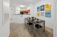 Modern apartment dining area with sleek table set for four, open kitchen, and motivational wall art for an inspiring living space.