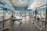 Spacious and modern gym with high ceilings, state-of-the-art equipment, and large windows offering natural light.