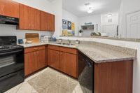 Modern kitchen with sleek black appliances, granite countertops, and rich wood cabinetry, offering a warm and inviting cooking space.