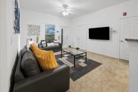 Modern living room with stylish gray sofas and vibrant yellow pillows, featuring contemporary wall art and a sleek glass coffee table on plush carpet.