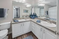 Elegant bathroom featuring a dual-sink vanity, stylish decor, and modern lighting with a glimpse into a chic adjacent room.