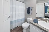 Elegant bathroom featuring a modern sink, stylish countertop, and a chic blue and white shower curtain. The cozy ambiance is enhanced by soft lighting and high-quality fixtures.