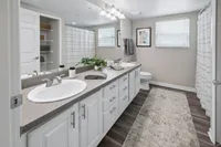 Elegant bathroom featuring dual sinks, modern fixtures, and chic decor with ample storage and warm lighting.