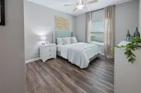 Charming bedroom with elegant decor featuring a cozy bed, modern nightstand, and natural light through large windows, perfect for relaxation.