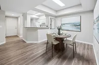 Elegant dining area with modern decor, featuring a round table set for four and a stylish open kitchen layout with sleek flooring.