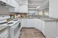 Bright modern kitchen with sleek white cabinetry, stainless steel appliances, and warm wood flooring, perfect for culinary enthusiasts.