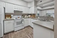 Chic modern kitchen with sleek white cabinetry, stainless steel appliances, and elegant countertops, accented by a stylish rug and open layout.