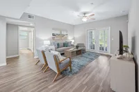 Bright and inviting living room with elegant hardwood floors, modern furniture, and abundant natural light through patio doors.