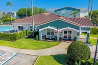 Charming apartment complex with lush landscaping, inviting swimming pool, and cozy seating under shaded porch.