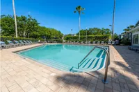 Inviting outdoor pool with pristine water, surrounded by lush greenery and stylish lounge chairs, perfect for relaxation.